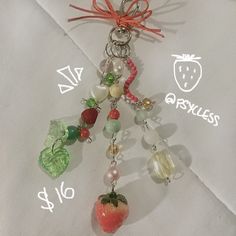 a key chain with fruit charms hanging from it's side on top of a white cloth