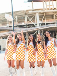 The perfect outfit for game day! Our Orange & White Overall Bib Checkerboard Dress, part of our Tennessee Gameday Collection, will make you stand out in the crowd. With a fun, quirky design and comfortable fit, you'll be the talk of the tailgate party. Go Vols! Trucker Hat Fashion, Football Spirit, Go Vols, Orange Amp, Gameday Dress, Tailgate Party, Heel Slippers, Outerwear Vest, The Talk