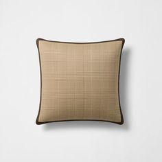 a tan and brown plaid pillow on a white wall with a black trim around the edges