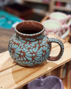 a blue and brown vase sitting on top of a wooden table next to other pottery