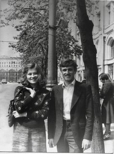 an old black and white photo of two people standing next to each other near a tree