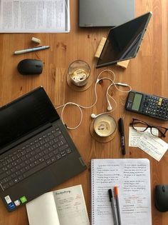 an open laptop computer sitting on top of a wooden table next to other office supplies