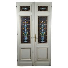 two white doors with stained glass designs on the front and side panels in different colors