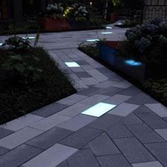 the walkway is lit up at night with blue lights on it and plants in pots