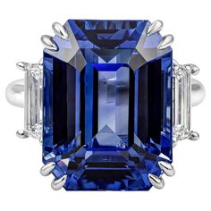 An elegantly made and rare three-stone engagement ring, showcasing an emerald cut heated blue sapphire weighing 26.14 carats. Accented by two step-cut trapezoid diamonds weighing 1.20 carats total. Finely made with a polished platinum mounting. The center stone is certified by GRS as Ceylon/Sri Lankan origin. Size 6.25 US, resizable upon request. Roman Malakov is a custom house, specializing in creating anything you can imagine. If you would like to receive a special quote on a custom piece, ple Emerald Cut Sapphire Ring, Sapphire And Diamond Engagement Ring, Diamond Sapphire Engagement Ring, Ceylon Blue Sapphire, Ring Emerald Cut, Sapphire Engagement Rings, Heritage Jewellery, Historical Jewellery, Silver Anniversary