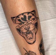 a black and white tattoo on the leg of a person with a cat's head