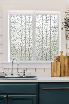 a kitchen sink under a window next to a counter top with cutting boards on it