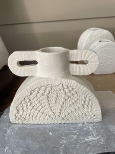 two white vases sitting on top of a table