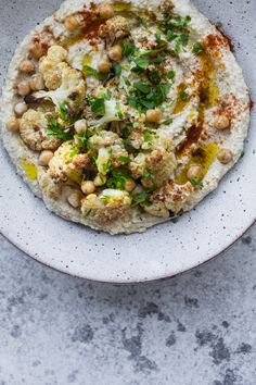 a white plate topped with hummus, chickpeas and garbanzo sauce