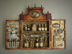 an old wooden cabinet filled with bottles and other items on top of a table next to a wall