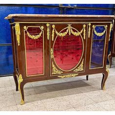 an ornate wooden cabinet with red glass doors