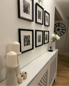 a white shelf with pictures and candles on it next to a vase filled with flowers