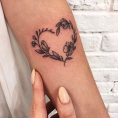 a woman's arm with a heart shaped flower tattoo on the left inner arm