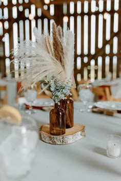 a vase with some feathers in it sitting on a table next to plates and glasses