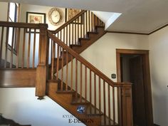 a wooden stair case next to a clock on the wall