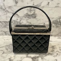 Description: This is beautiful 1996 Fall Collection vintage black patent leather Chanel vanity box purse featuring a diamond quilted pattern, top handle, two silver logo CC Chanel logo buttons on side, and a silver-plated rim on the top of the bag which reads ‘CHANEL PARIS’. The bag has a unique flap opening with a silver logo CC closure. As seen in Karl Lagerfeld’s 1996 Beverly Hills Hotel Campaign photographed on model Shalom Harlow. Designer: Chanel  Authenticity number: 4089174 Year: Fa Black Box Bag For Shopping, Pre-owned Top Handle Bags For Formal Occasions, High-end Formal Box Bag With Dust Bag, High-end Black Rectangular Box Bag, Vintage Pre-owned Formal Bags, Elegant Pre-owned Rectangular Bag, Formal Box Bag With Detachable Handle And Rectangular Case, Formal Square Box Bag With Original Box, Designer Square Box Bag For Evening