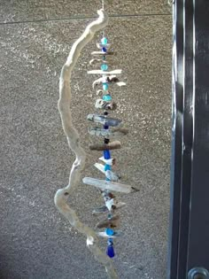 a wind chime hanging from the side of a building with rocks and glass beads