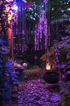 an outdoor garden with purple lights and rocks on the ground, surrounded by trees and plants