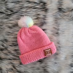 a pink hat with a white pom - pom on top