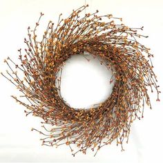 a wreath with dried flowers hanging on a white wall in the shape of a circle