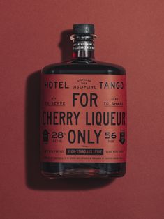 a bottle of liquor sitting on top of a red table next to a pink wall