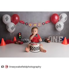 a little boy sitting on top of a cake in front of balloons and streamers