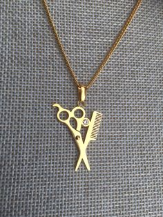 a gold necklace with scissors and a comb on it