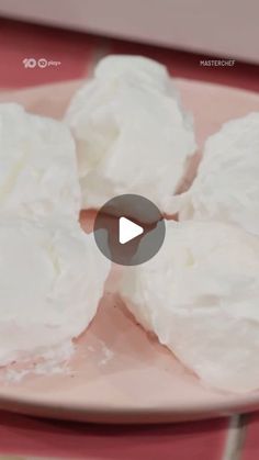 a pink plate topped with white frosting on top of a table