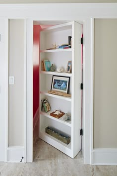 a white book shelf filled with books on top of a tiled floor next to a doorway