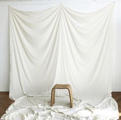 a chair sitting on top of a bed covered in white sheets and blankets next to a wall