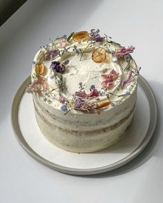 a white cake with flowers on it sitting on a plate