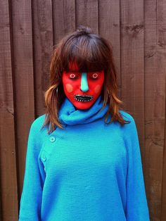 a woman wearing a blue sweater and red painted face