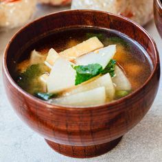 a wooden bowl filled with soup on top of a table