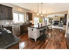 a large kitchen with an island in the middle and wooden flooring on the other side