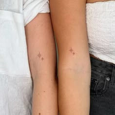 two people with matching tattoos on their arms, one is holding the other's arm