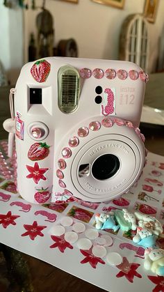 a white camera sitting on top of a table covered in pink and white decorations,