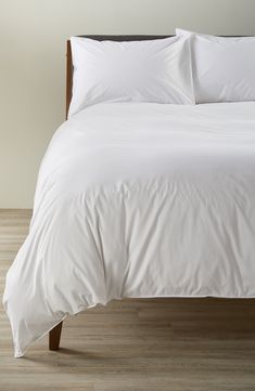 a bed with white sheets and pillows in a room