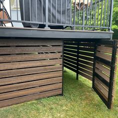 a wooden bench sitting on top of a lush green field next to a metal fence