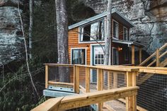 a small wooden cabin in the woods with stairs leading up to it's entrance