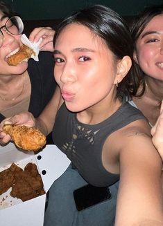 three women are eating food at a table