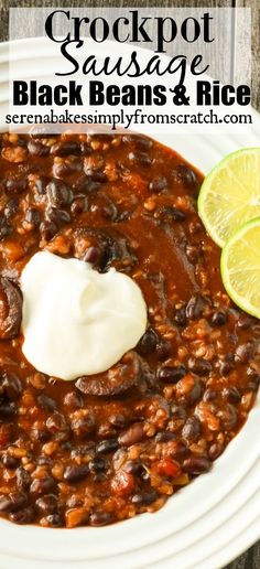 a white plate topped with black beans and sour cream next to a lime slice on the side