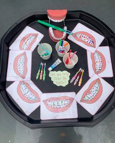 a tray with toothbrushes, cups and other items on it that are arranged in the shape of a mouth