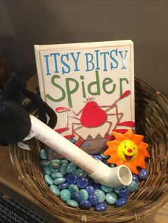 there is a book and some toys in a basket on top of the table with rocks