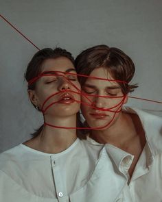 two people with their faces covered by red string