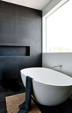 a white bath tub sitting in a bathroom next to a window with potted plants