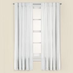 a window with white curtains hanging on the wall