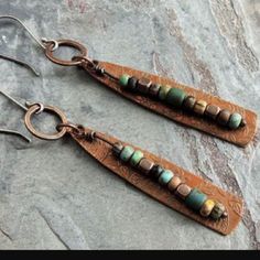 two pairs of leather earrings with beads on them sitting on top of a stone surface