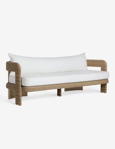 a wicker couch with white pillows on it