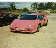 a pink sports car parked next to other cars