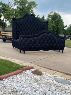 a black couch sitting on top of a pile of rocks in front of a park